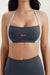Woman wearing a dark gray sports bra with 'SET' branding on a light background