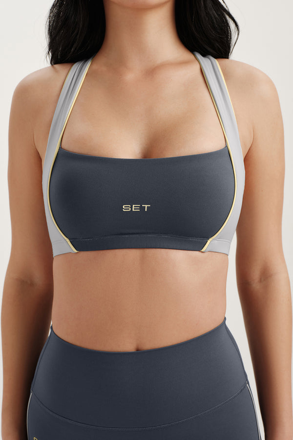 Woman wearing a dark gray sports bra with 'SET' branding on a light background