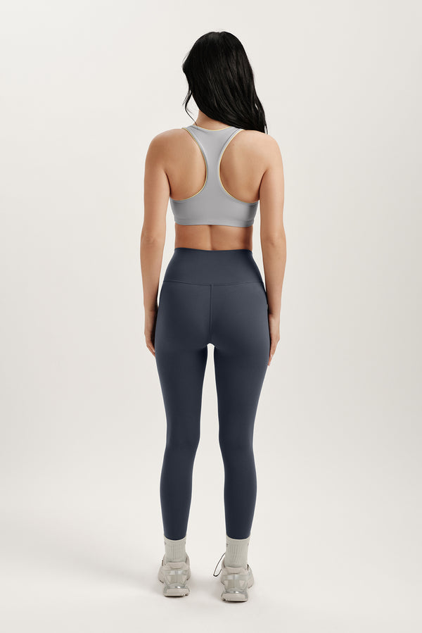 Person wearing a gray sports bra and dark gray leggings on a white background
