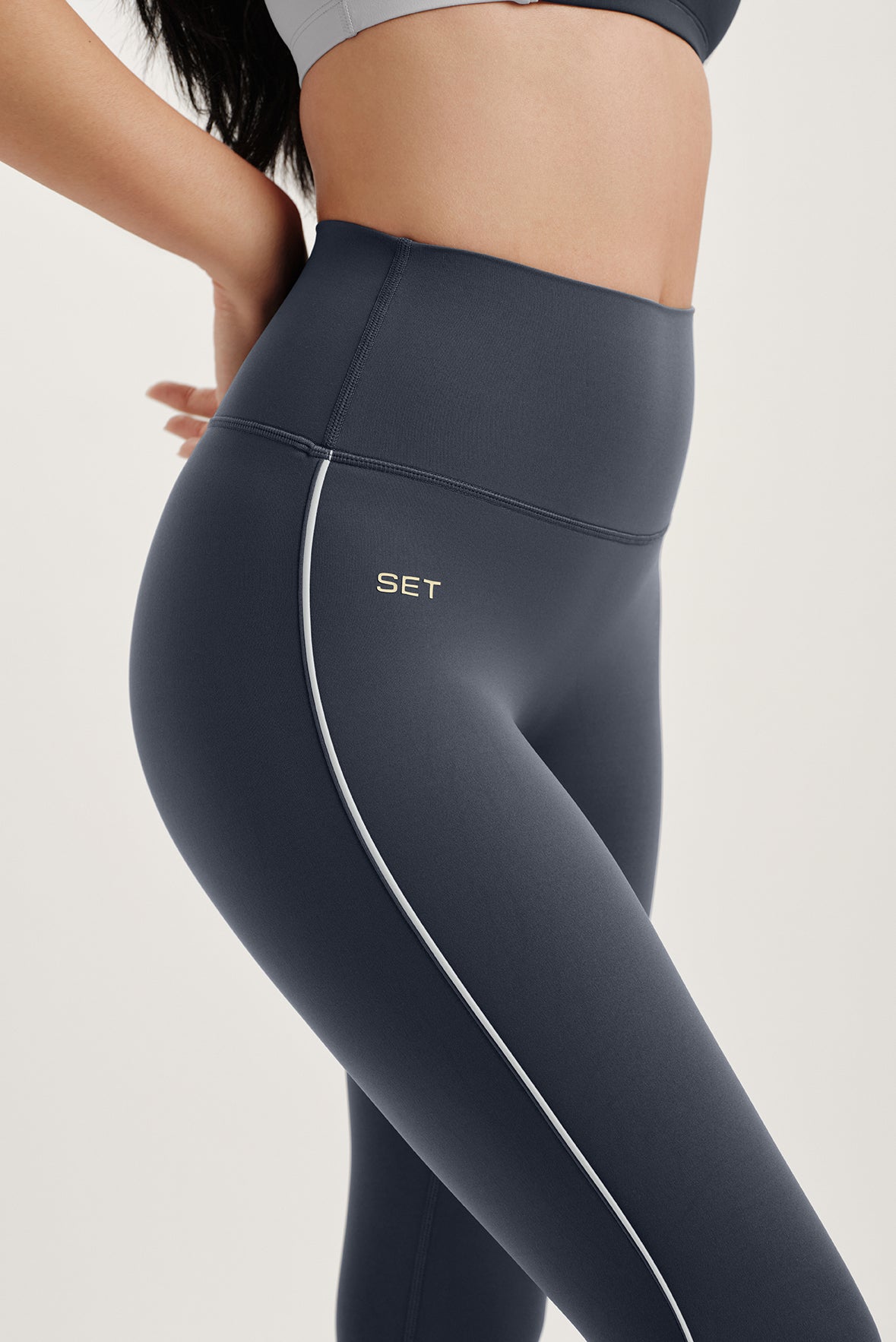Close up of gray leggings with 'SET' brand logo and a white stripe 