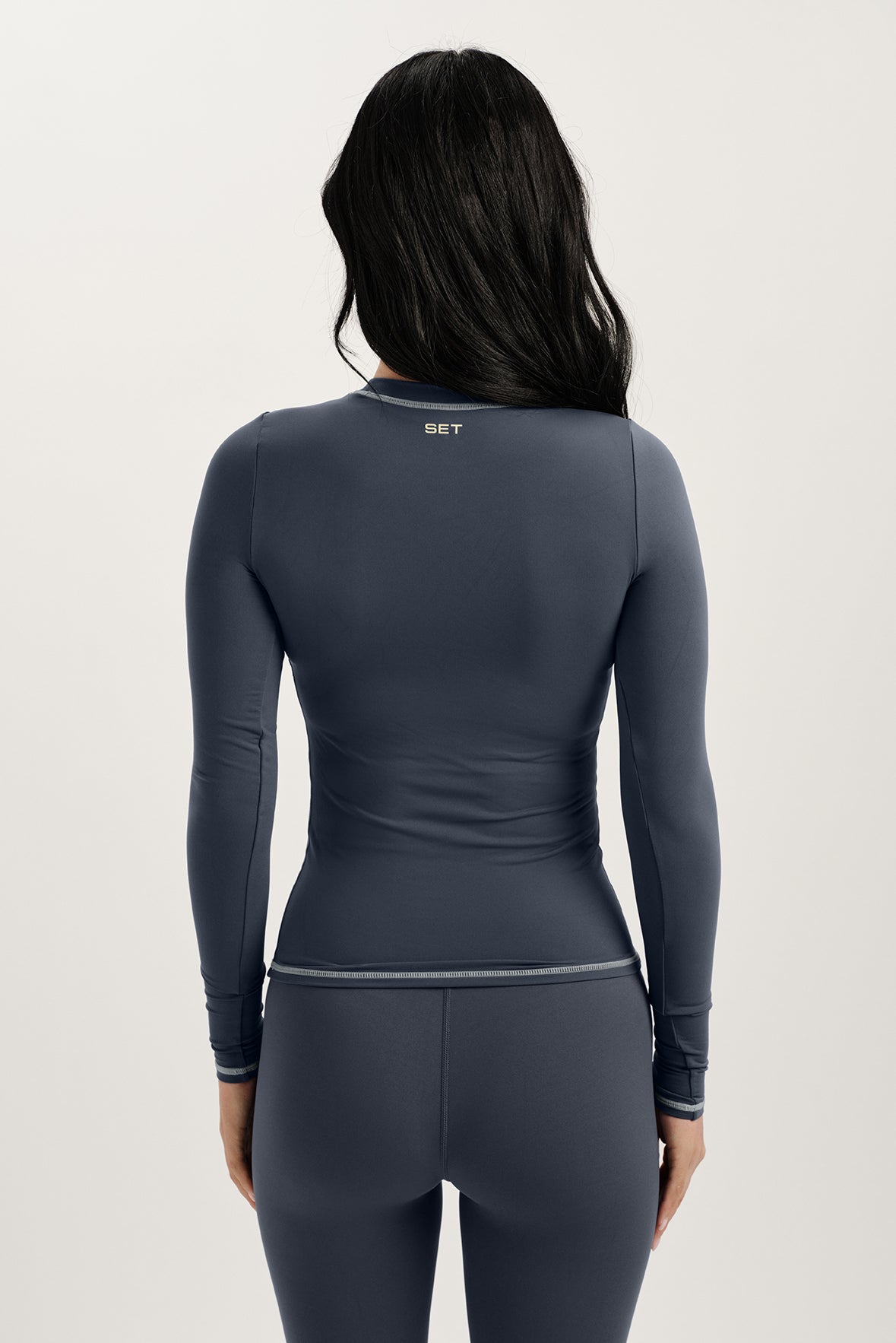 Person wearing a dark gray long-sleeve top and pants with 'SET' branding on a light gray background