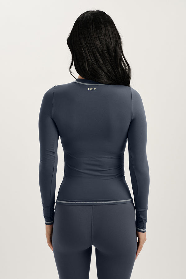 Person wearing a dark gray long-sleeve top and pants with 'SET' branding on a light gray background