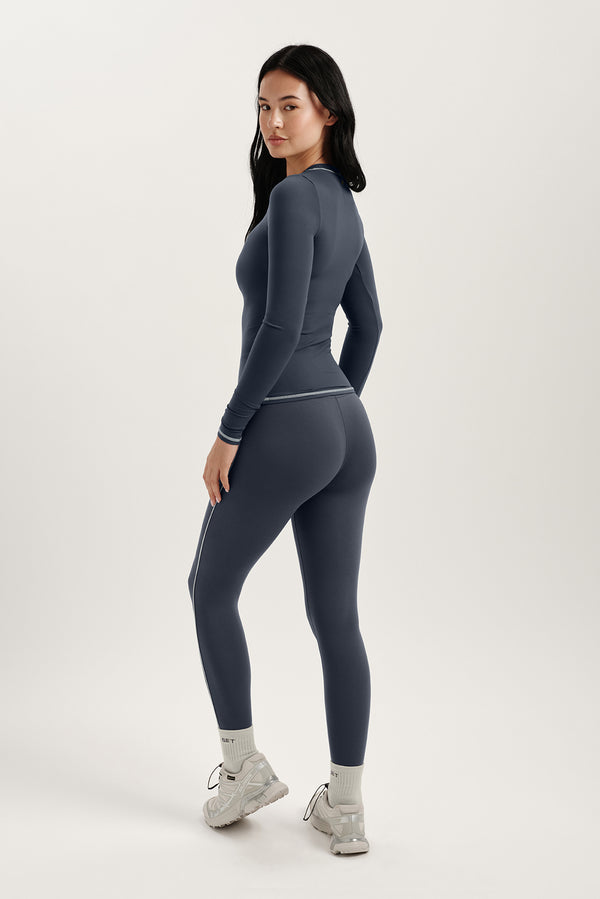 Woman wearing a gray athletic outfit on a white background