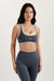 Woman wearing a gray sports bra and leggings with 'SET' branding on a light background <model-info>Jasmine wears a size S and is 5’8, 25” waist, 32C bust.</model-info> 