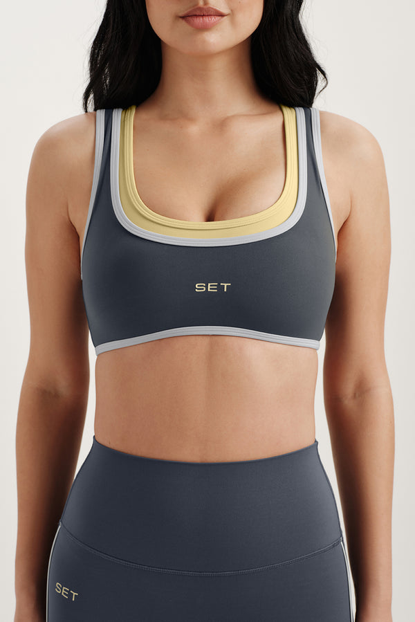 Woman wearing a gray sports bra and leggings with 'SET' branding on a light background
