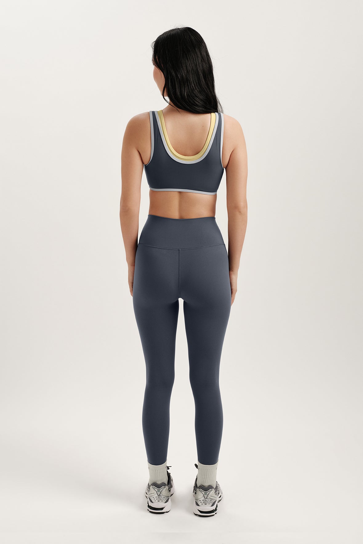 Person wearing a gray sports bra and leggings set on a white background