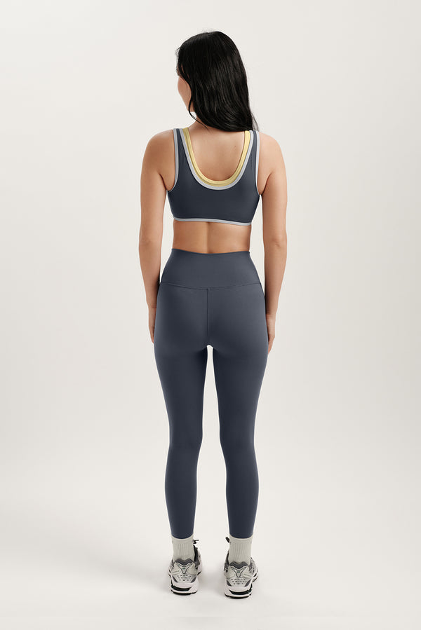 Person wearing a gray sports bra and leggings set on a white background
