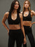 Two women wearing black sports bras and leggings on a gray background