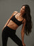 Woman wearing a black sports bra and leggings against a gray background