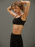 Woman wearing a black sports bra and leggings against a gray background