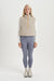 Woman wearing a beige insulated vest and gray leggings on a white background