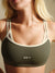 Woman wearing a green sports bra with 'SET' branding against a neutral background