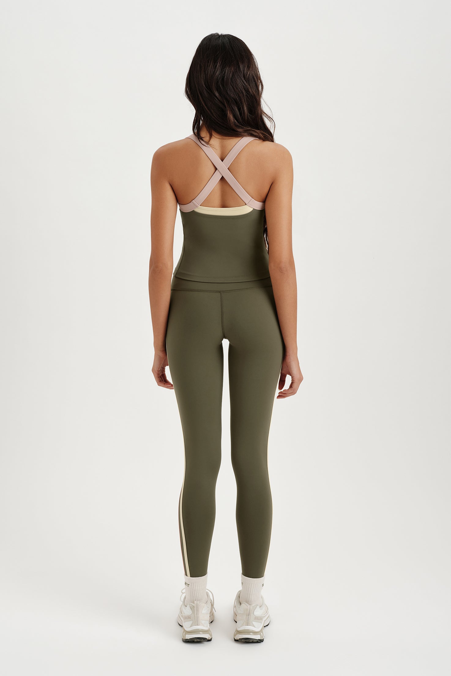 Person wearing a green athletic outfit with criss-cross straps on a white background