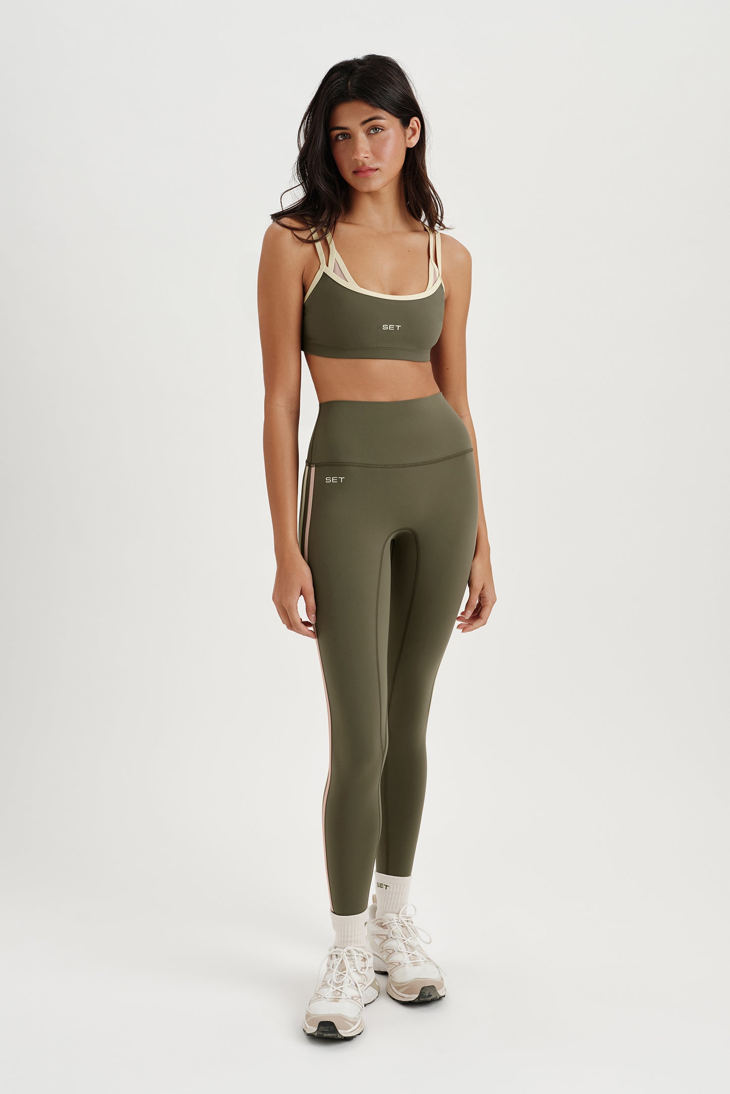 Woman wearing a green sports bra and leggings set on a white background
