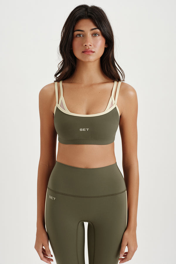 Woman wearing a green sports bra and leggings set on a white background 