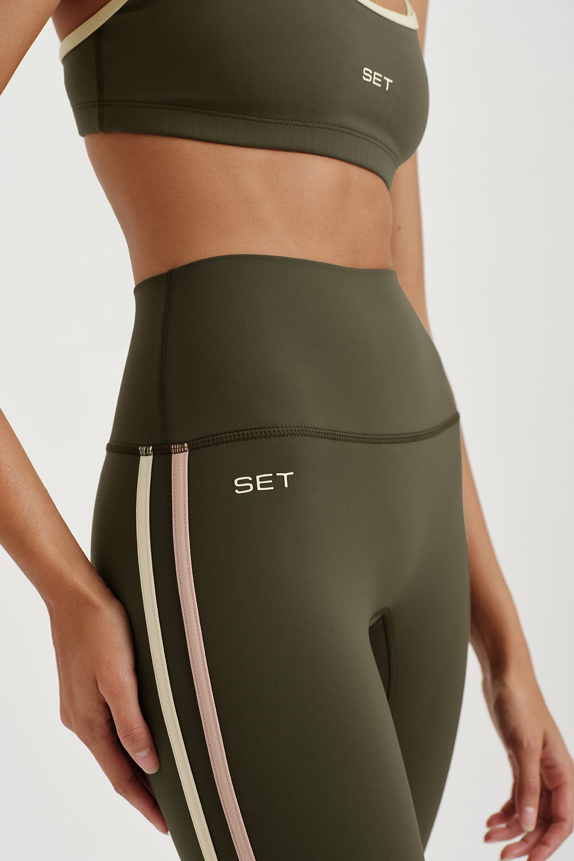 Olive green sports bra and leggings with 'SET' branding on a light gray background