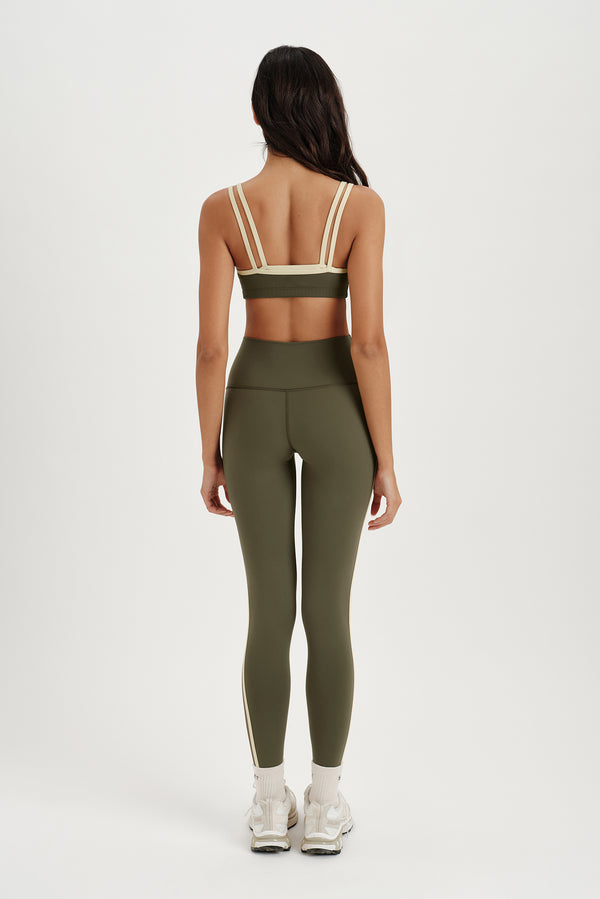 Person wearing a green sports bra and leggings set on a white background