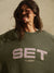 Person wearing a green sweatshirt with 'SET SUMMIT' text on a neutral background