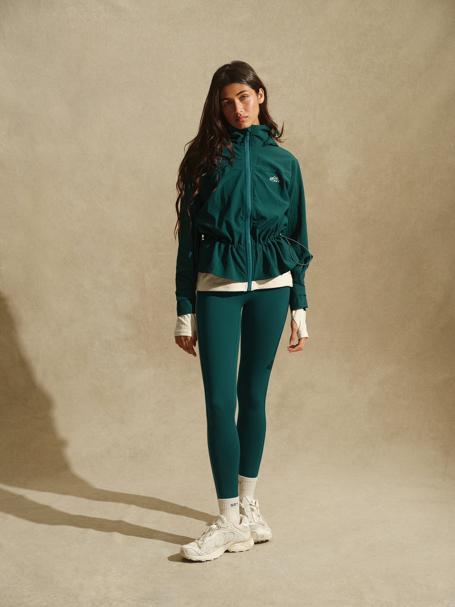 Woman wearing a green tracksuit with a beige background