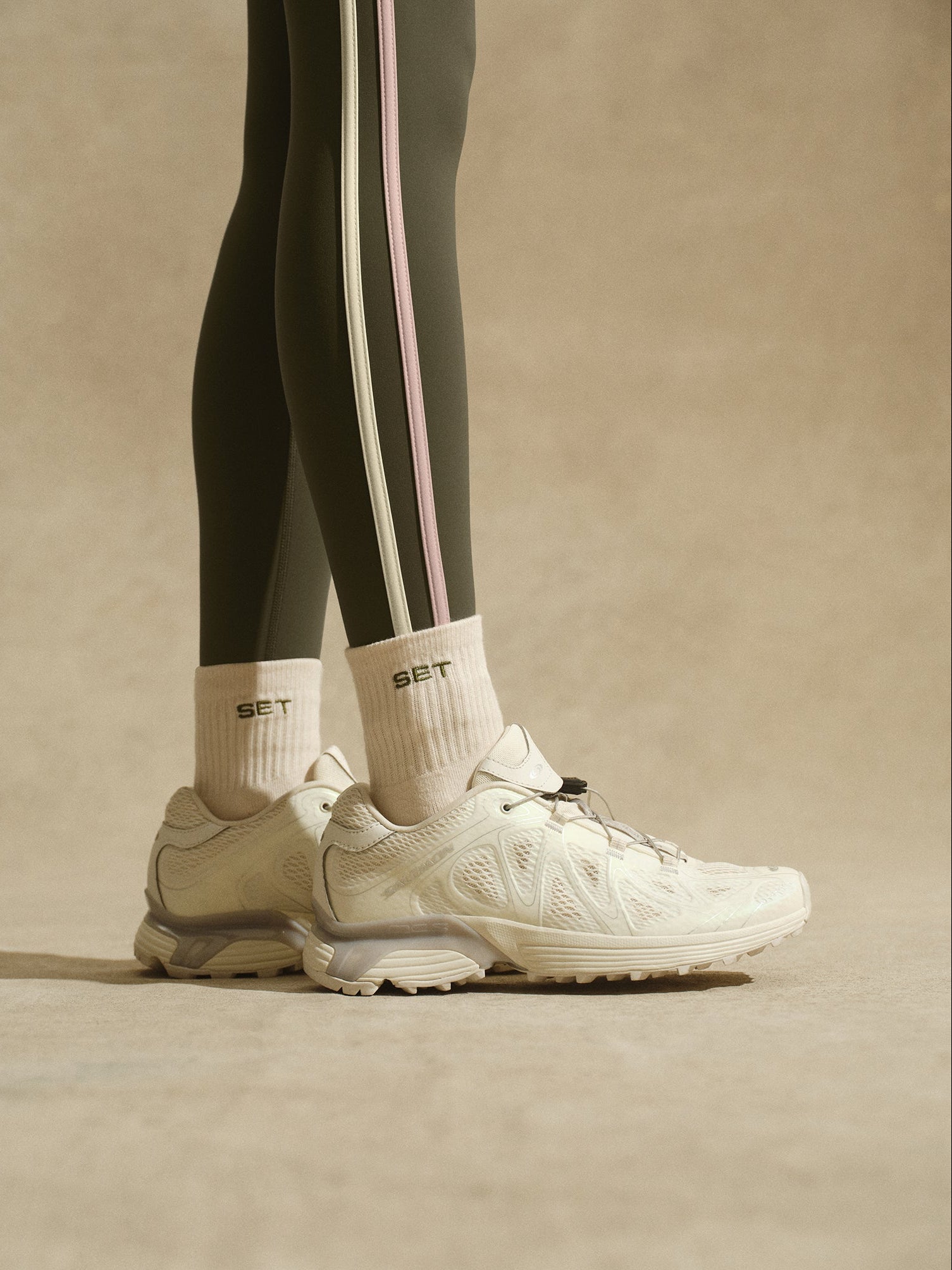 Person standing with green leggings with stripes and beige socks with 'SET' logo