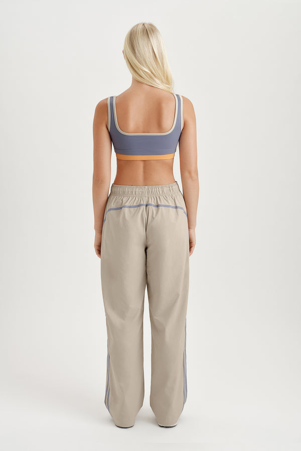 Person wearing a sports bra and track pants on a white background