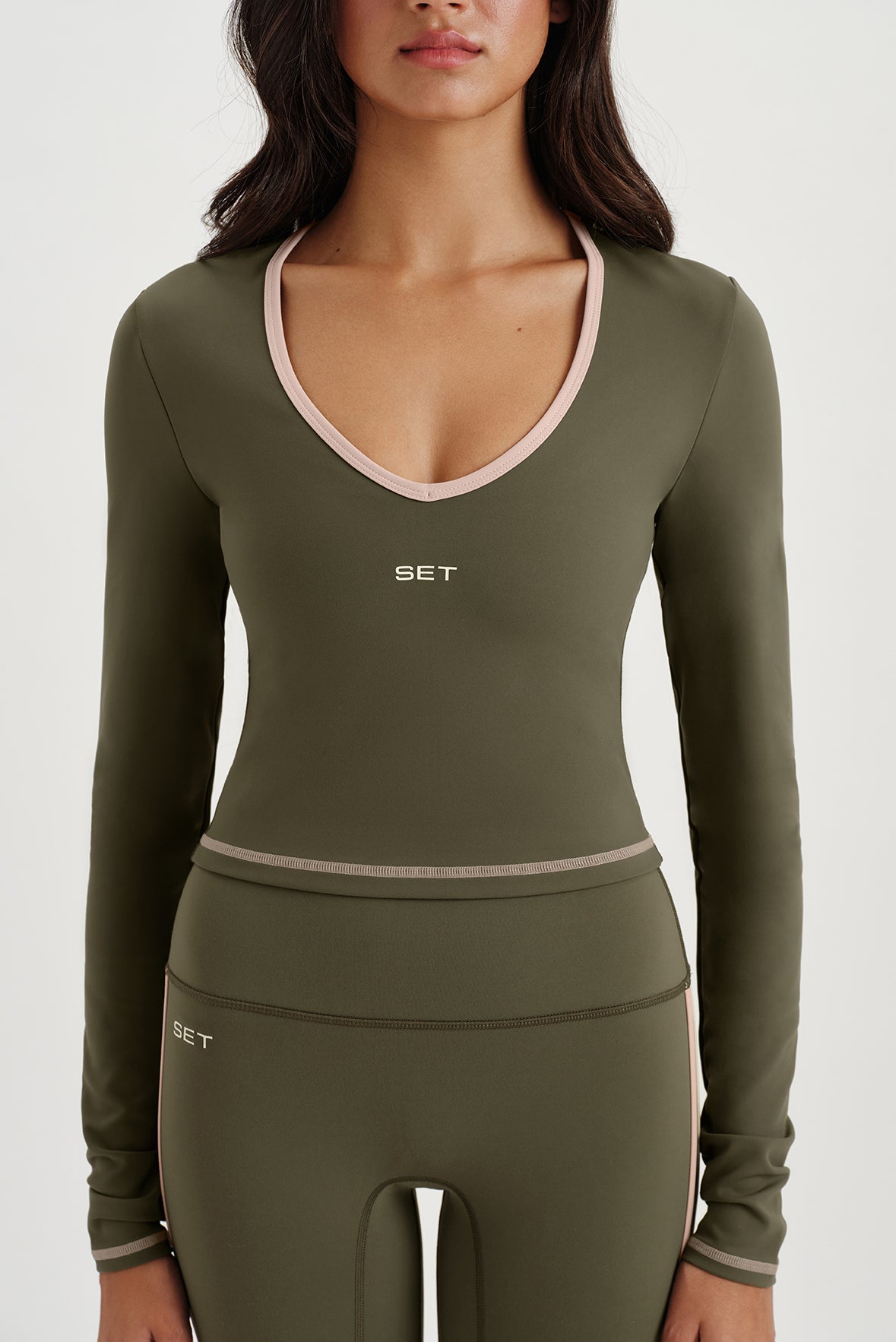 Woman wearing an olive green athletic outfit with 'SET' branding on a white background