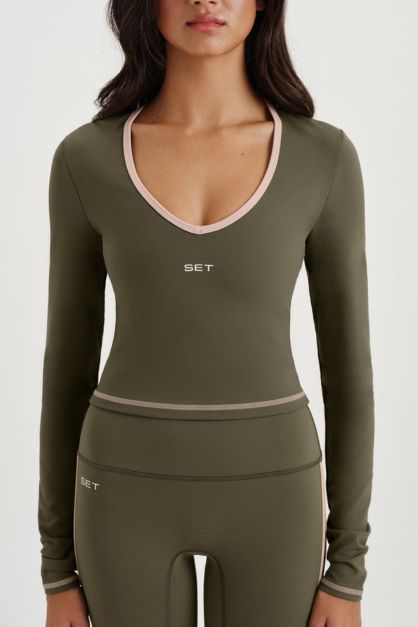 Woman wearing an olive green athletic outfit with 'SET' branding on a white background