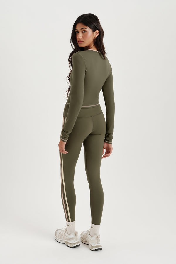 Woman wearing a green athletic outfit with white sneakers on a white background