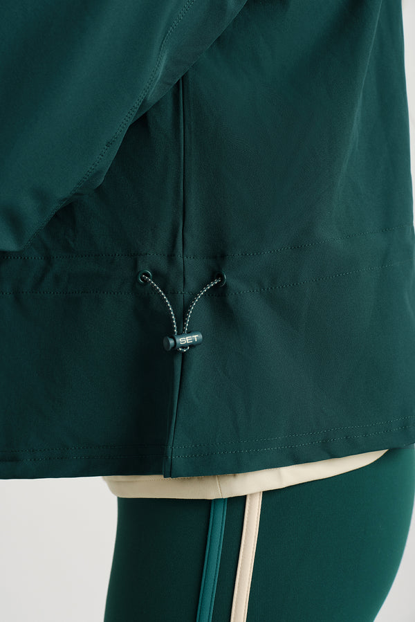 Close-up of a dark green jacket with a brand logo on a light background