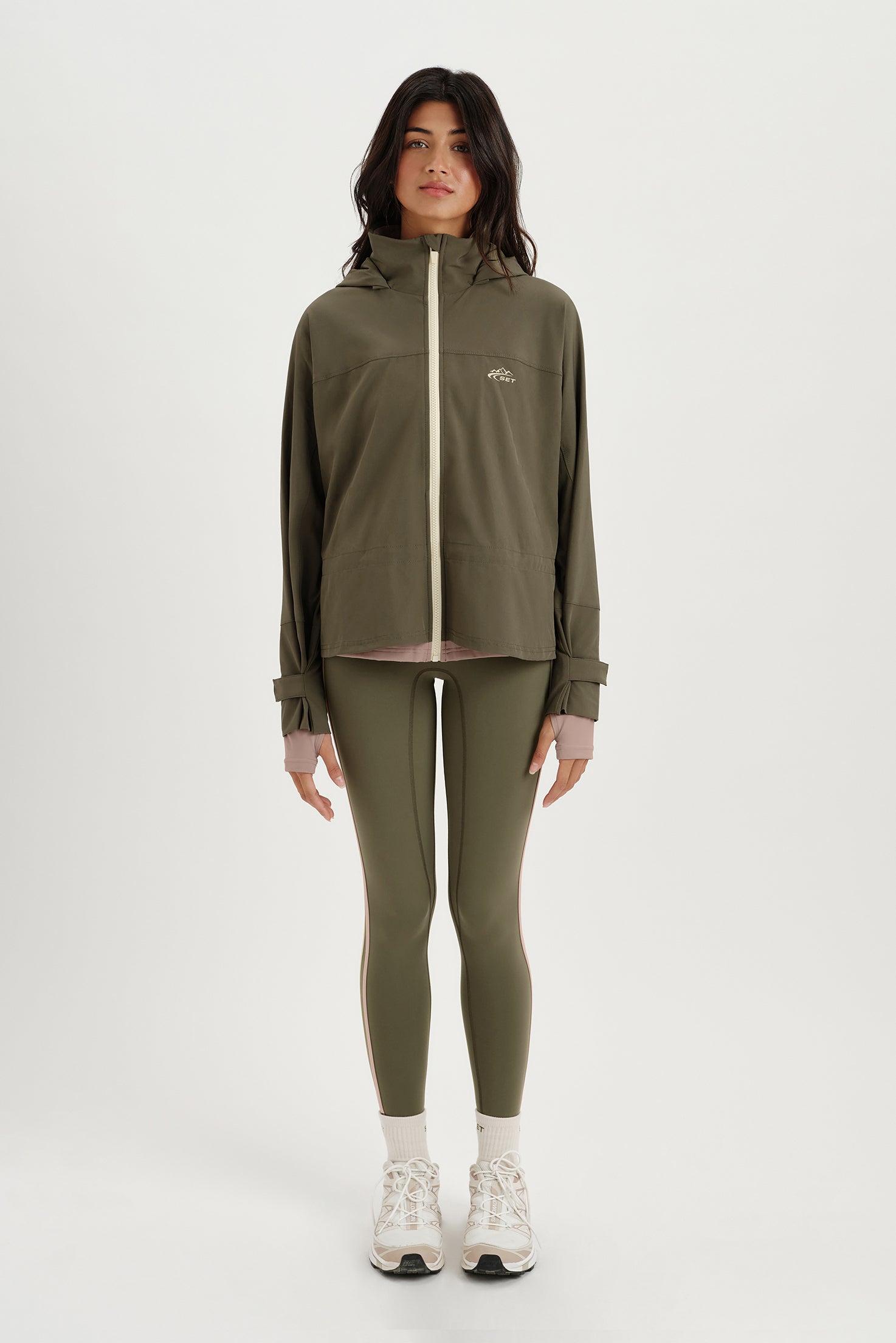 Person wearing a green tracksuit with a brand logo on a white background <model-info>Meeya wears a size XS and is 5’7, 23” waist, 32B bust.</model-info> 