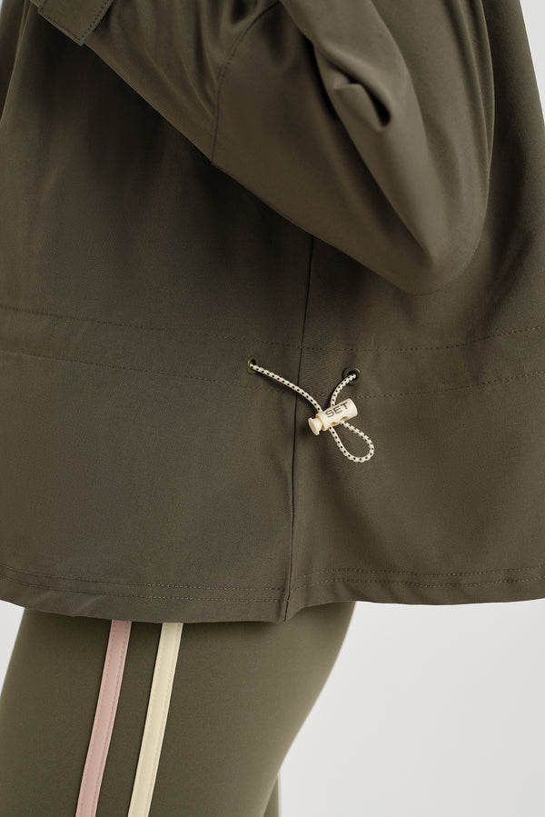 Close-up of a person wearing an olive green jacket with a hood, focusing on the drawstring detail.