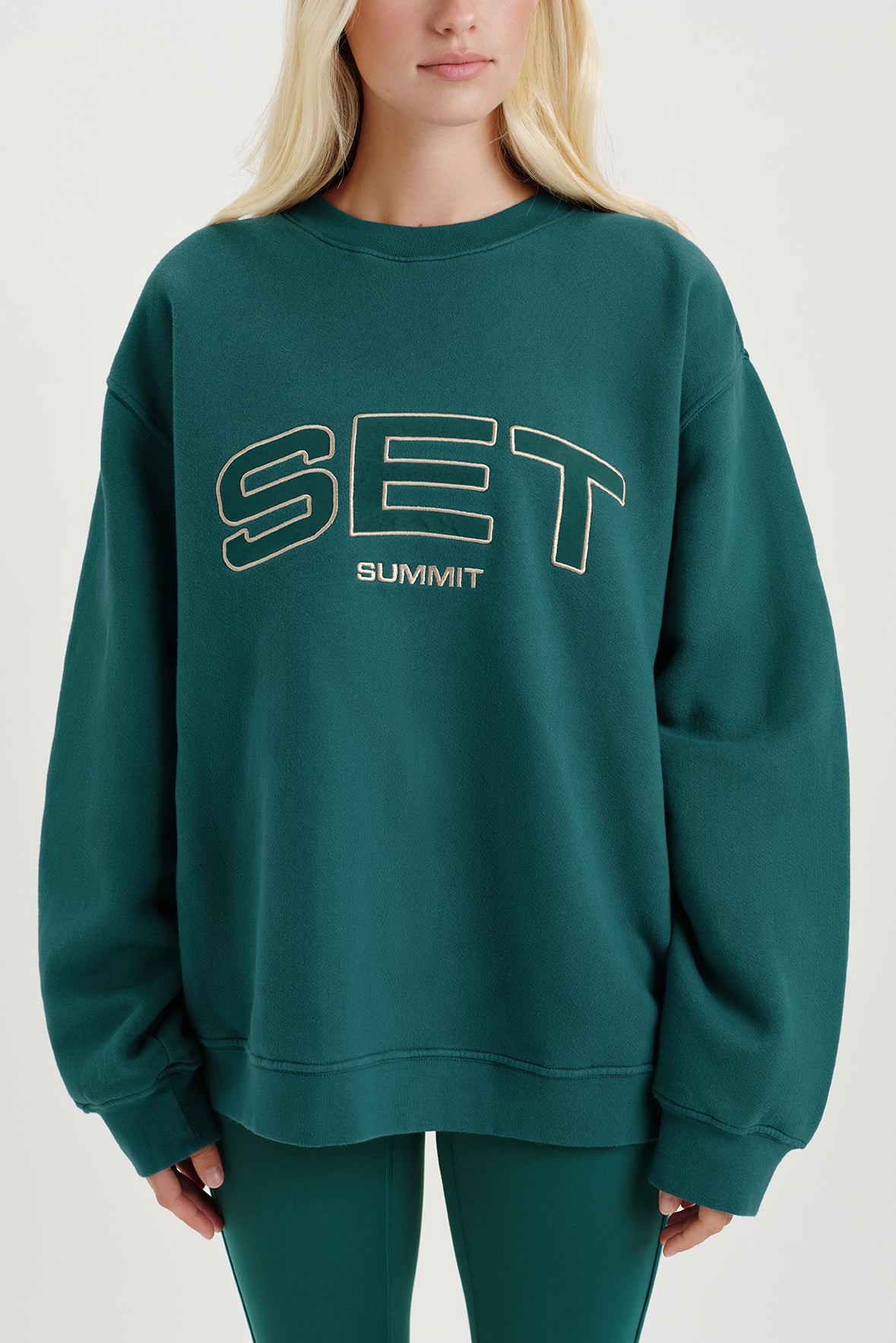 Person wearing a green sweatshirt with 'SET SUMMIT' text on a white background
