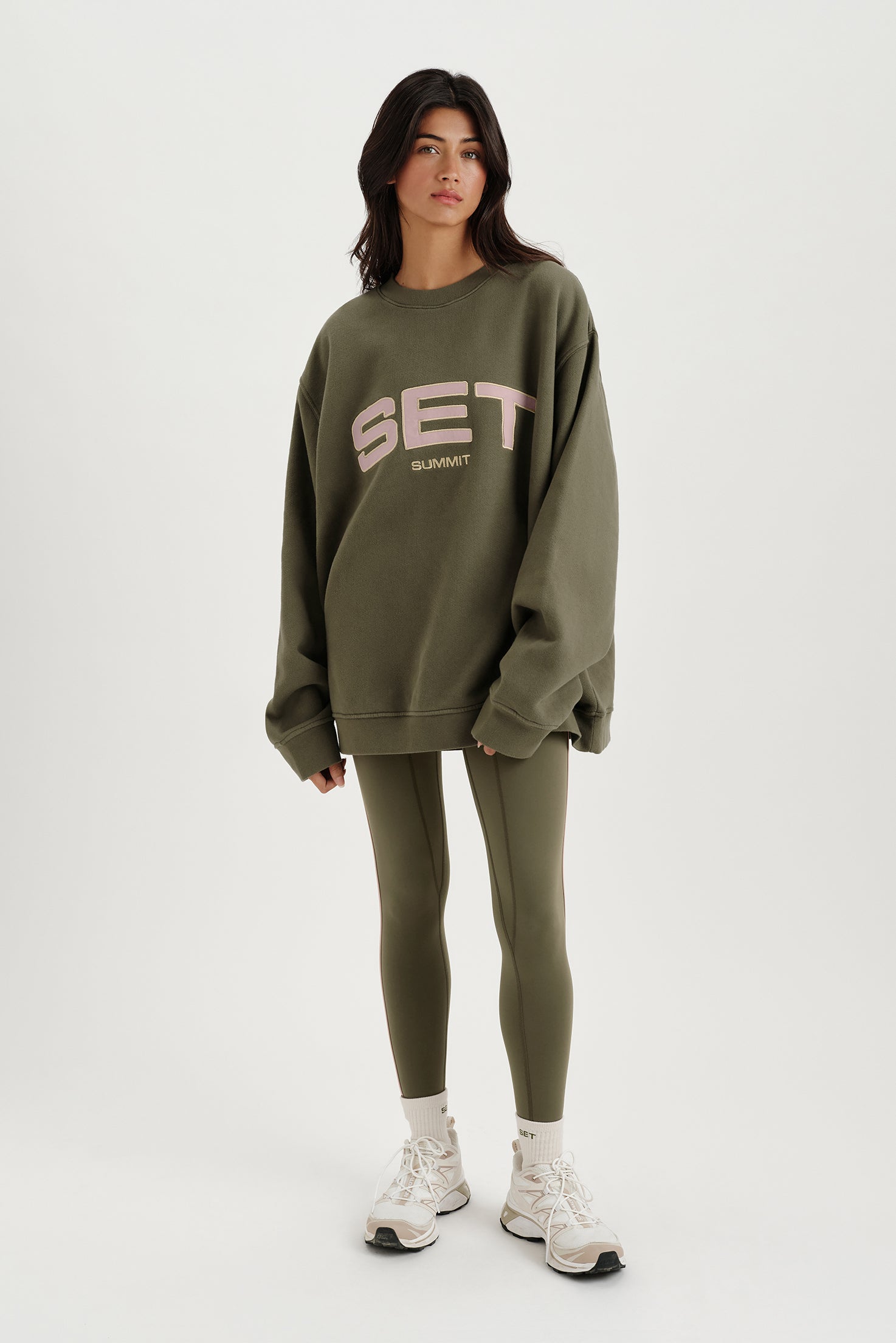 Person wearing a green 'SET' sweatshirt and leggings on a white background <model-info>Meeya wears a size XS and is 5’7, 23” waist, 32B bust.</model-info> 