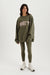 Person wearing a green 'SET' sweatshirt and leggings on a white background <model-info>Meeya wears a size XS and is 5’7, 23” waist, 32B bust.</model-info> 