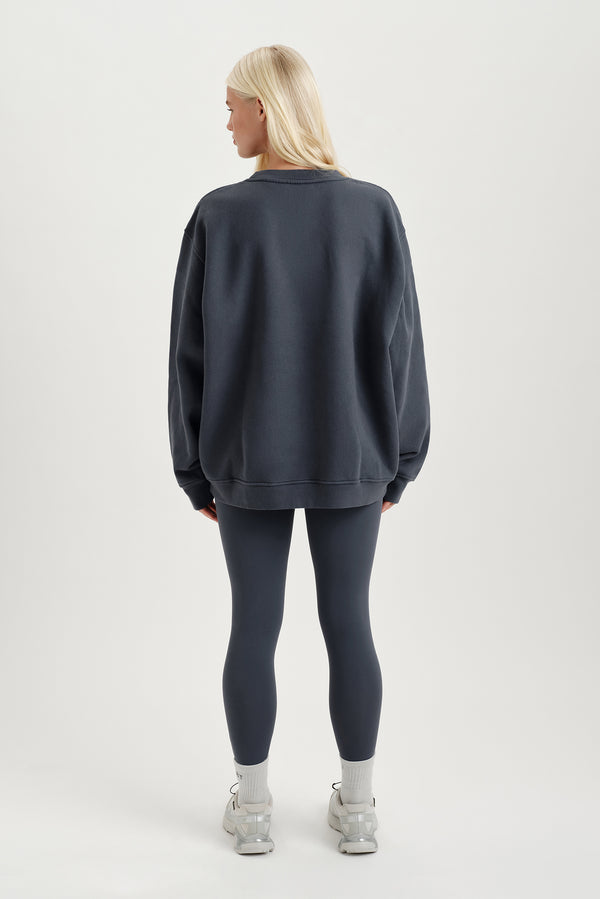 Person wearing a dark gray sweatshirt and leggings on a white background
