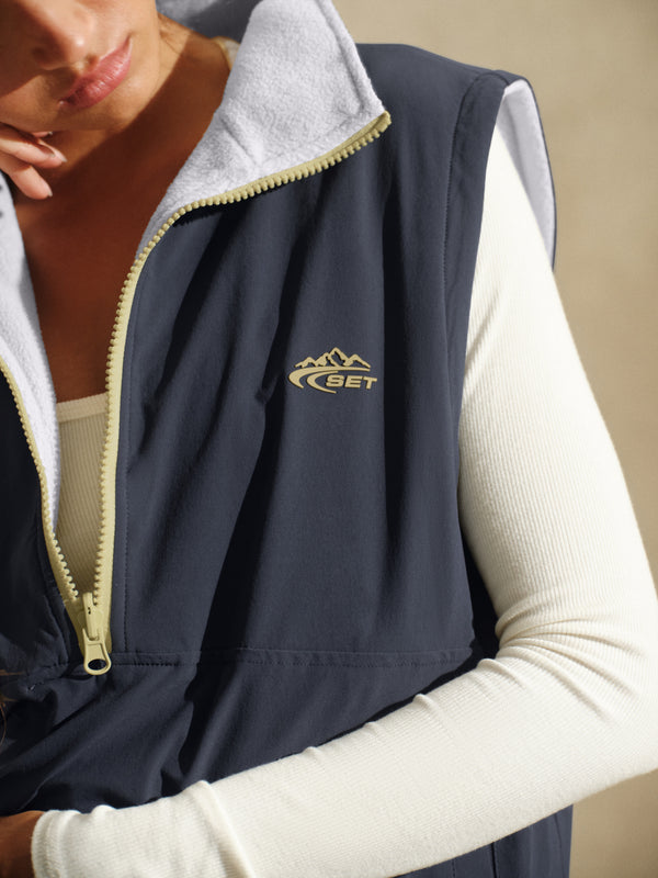 Gray vest with white long sleeve and a 'SET' brand logo in yellow 