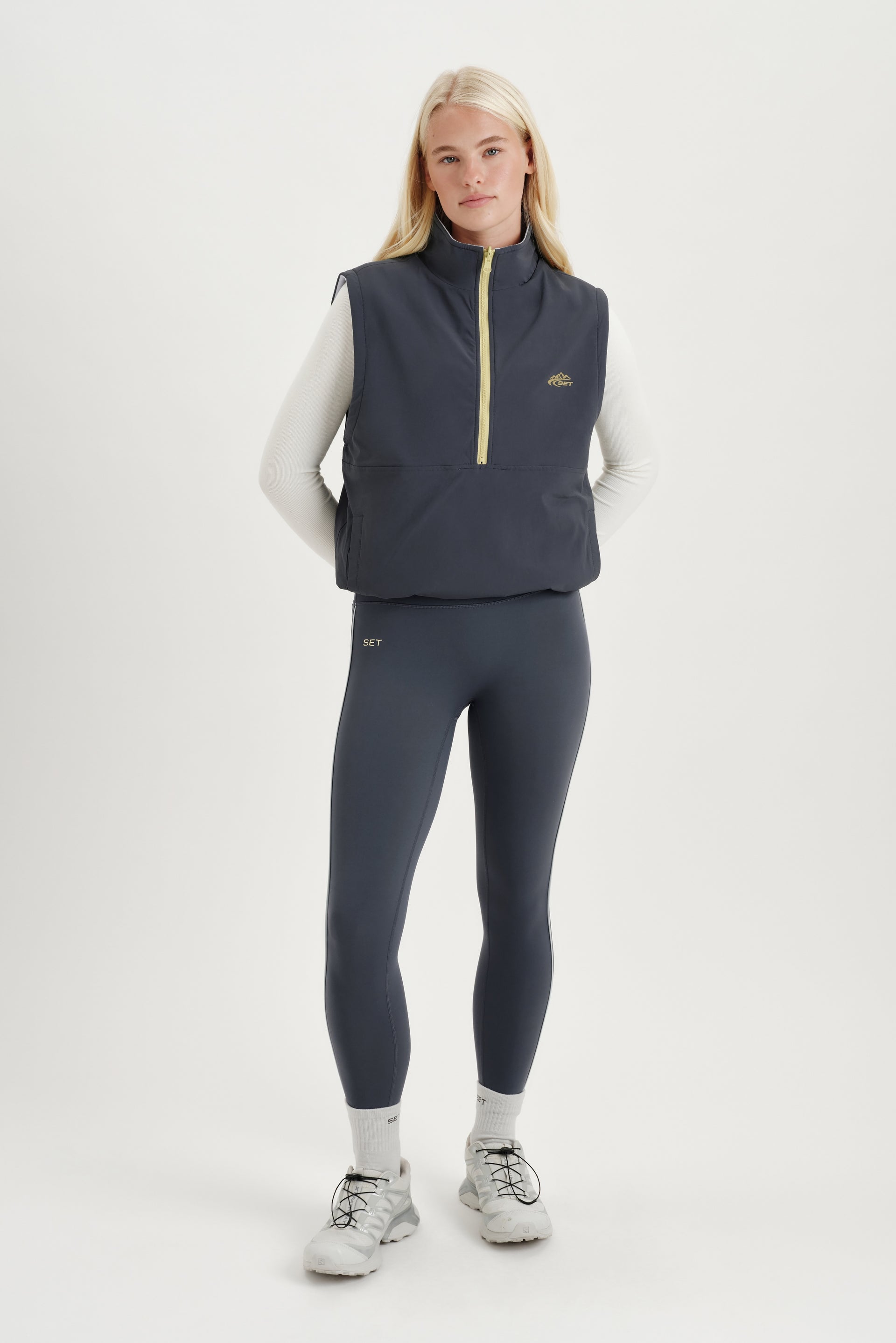 Woman standing with white long sleeve and gray vest on a white background  <model-info>Kathryn wears a size S and is 5’8½ , 24” waist, 33B bust.</model-info> 