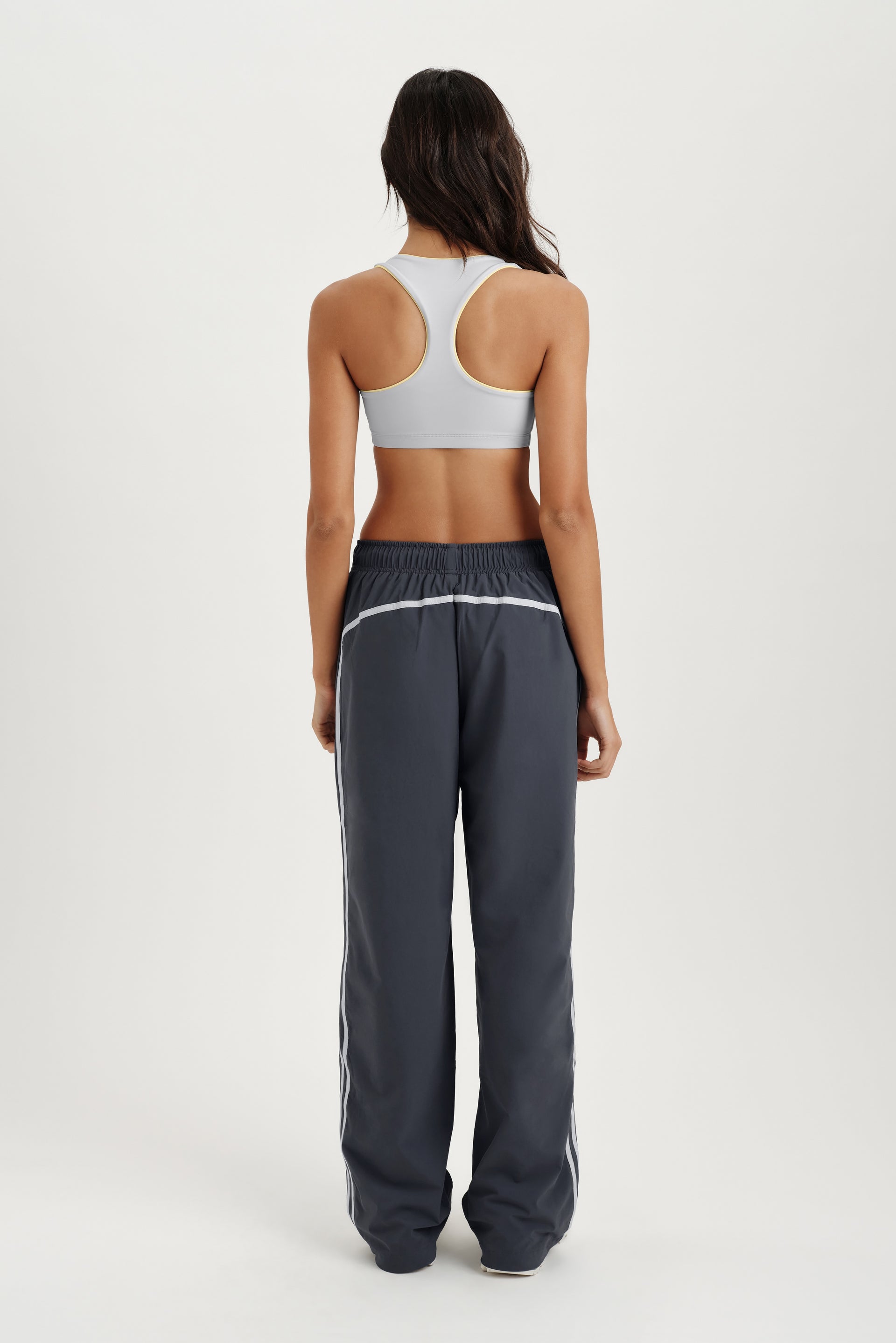 Person standing in gray track pants with light gray sports bra 