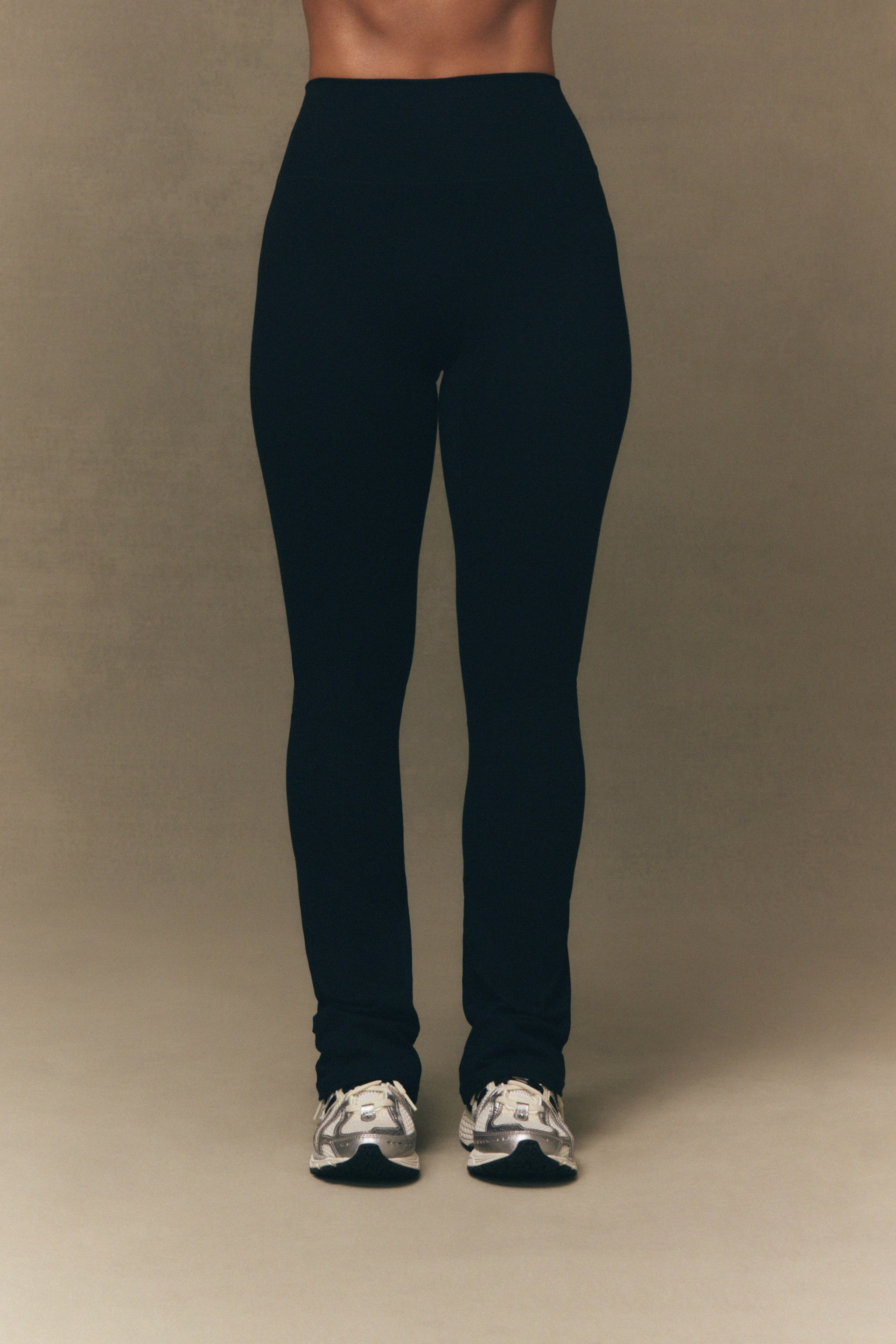 Person wearing black leggings on a beige background