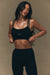 Woman wearing a black sports bra and leggings with 'SET' branding on a beige background <model-info>Jelene wears a size XS and is 5’7”, 23” waist, 32AB bust.</model-info>