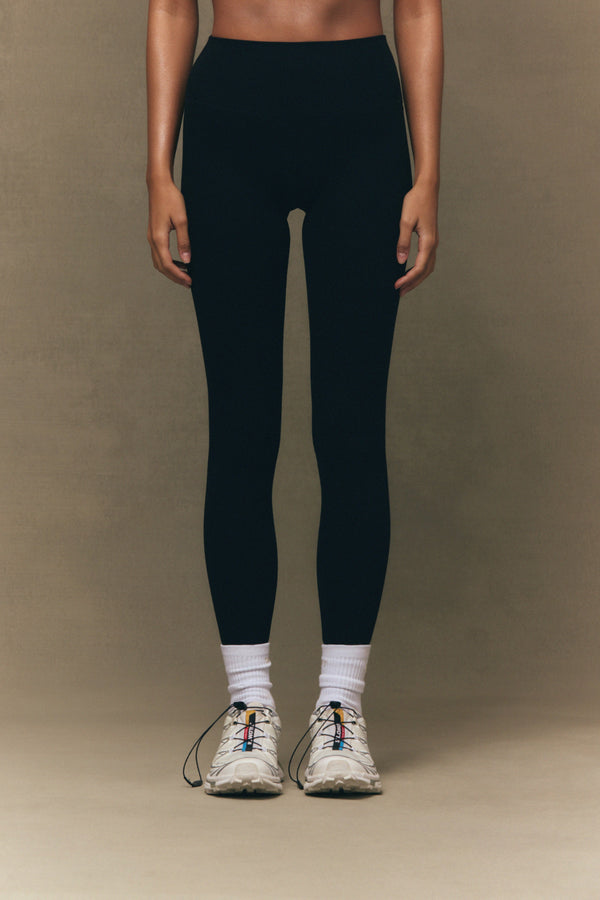 Person wearing black leggings and white sneakers on a brown background 