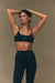 Woman wearing a black sports bra and leggings against a beige background