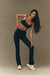 Woman in black athletic wear posing against a beige background <model-info>Jelene wears a size XS and is 5’7”, 23” waist, 32AB bust.</model-info>