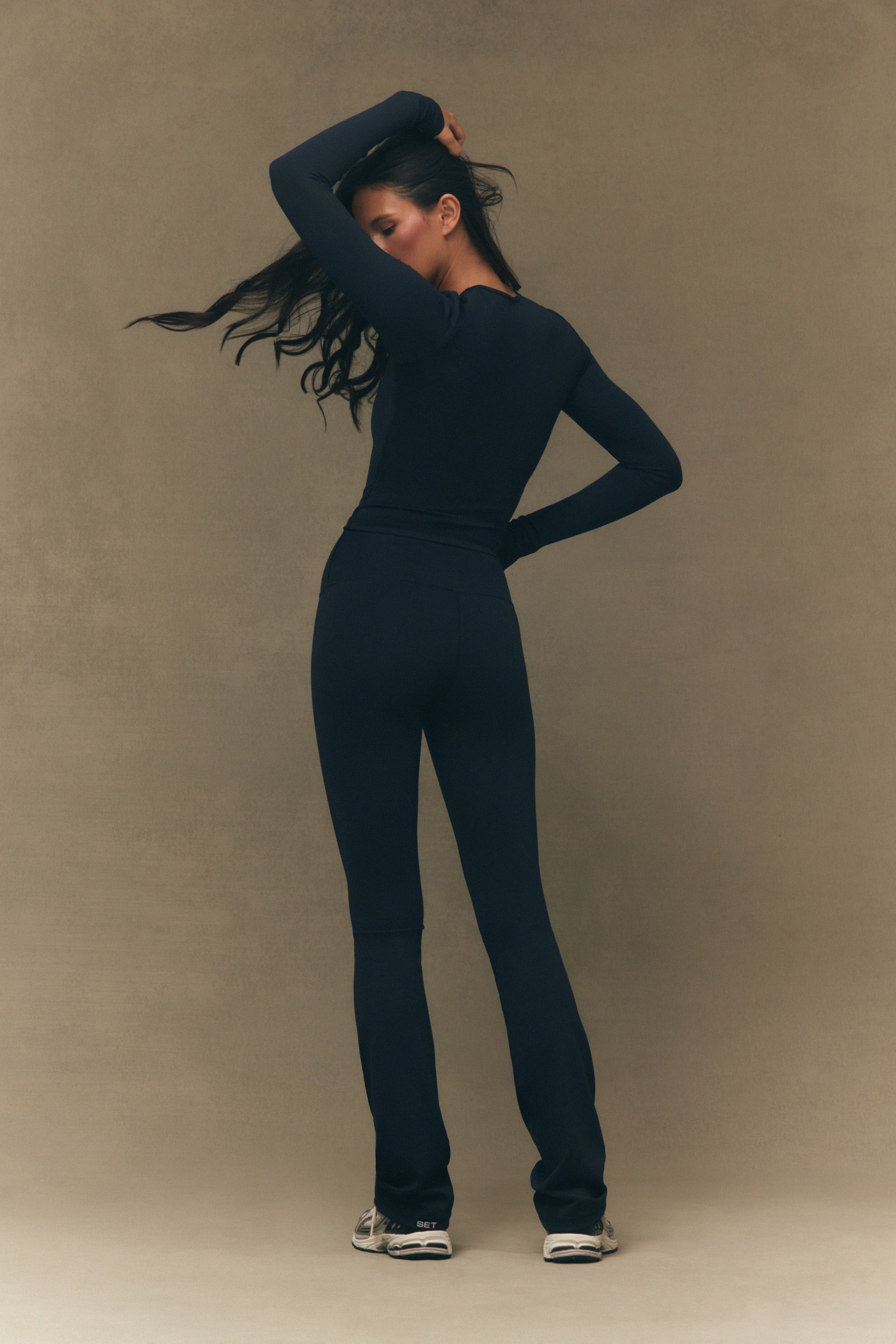 Person wearing a black outfit against a beige background