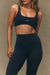 Woman wearing a black sports bra and leggings with 'SET' branding on a beige background