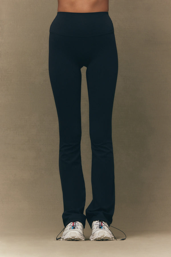 Person wearing black leggings on a beige background