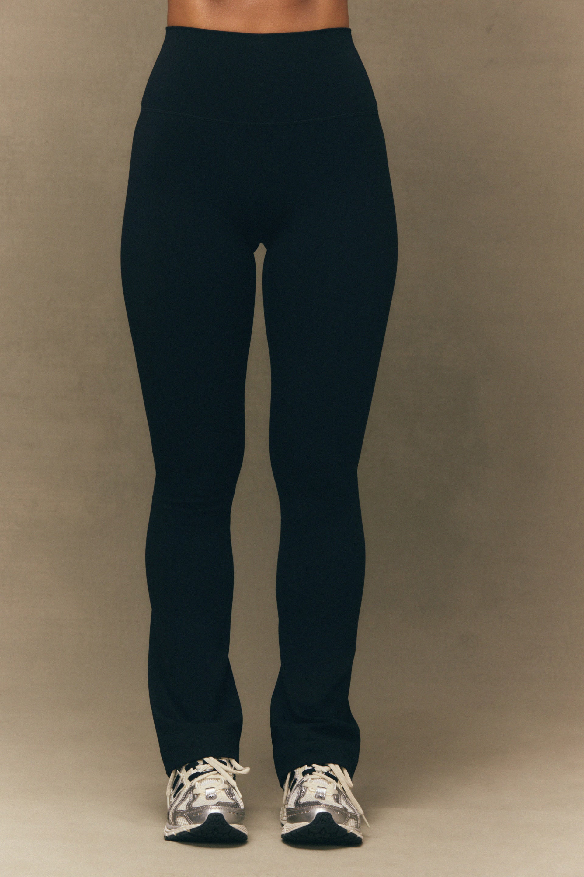 Person wearing black leggings on a beige background