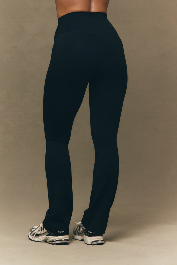 Person wearing black leggings on a beige background