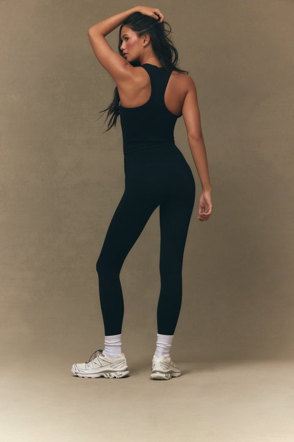 Woman wearing a black athletic outfit on a beige background