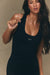 Woman wearing a black tank top with 'SET' branding against a beige background <model-info>Jelene wears a size XS and is 5’7”, 23” waist, 32AB bust.</model-info>